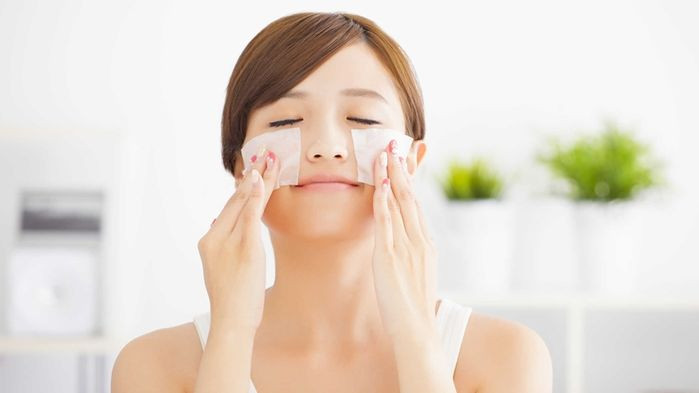 Người phụ nữ đang thoa kem chống nắng lên mặt, thể hiện bước chăm sóc da hàng ngày.